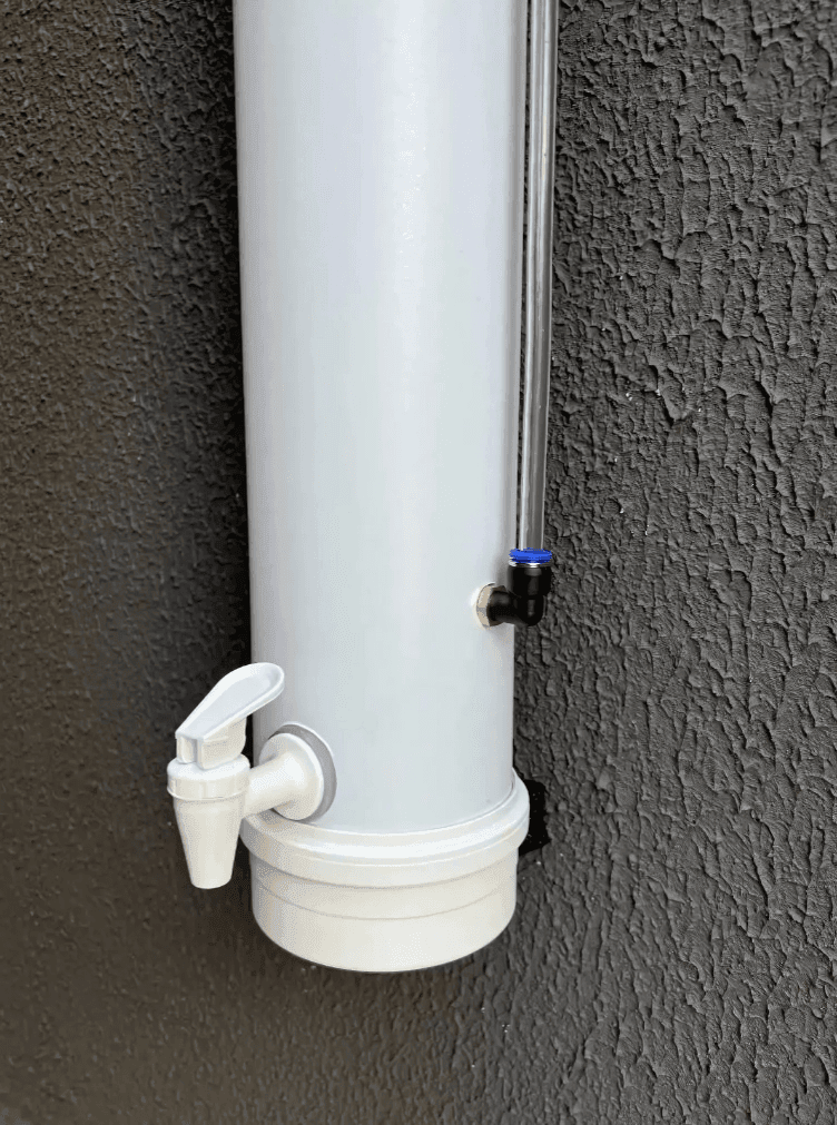 White cylindrical water filter with spout attached to a textured wall.