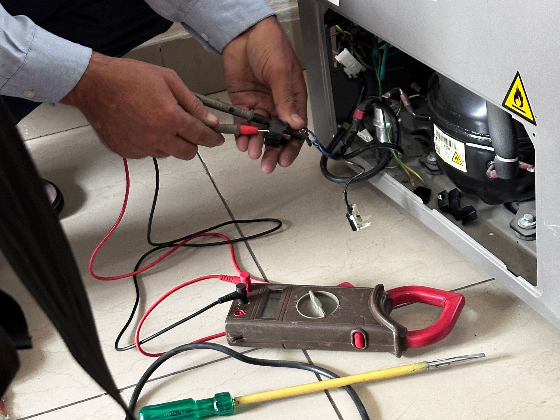 Imagem em close-up de um faz-tudo irreconhecível verificando a corrente elétrica do freezer na cozinha, recarregando compressor de gás, botijão de gás, refrigerante